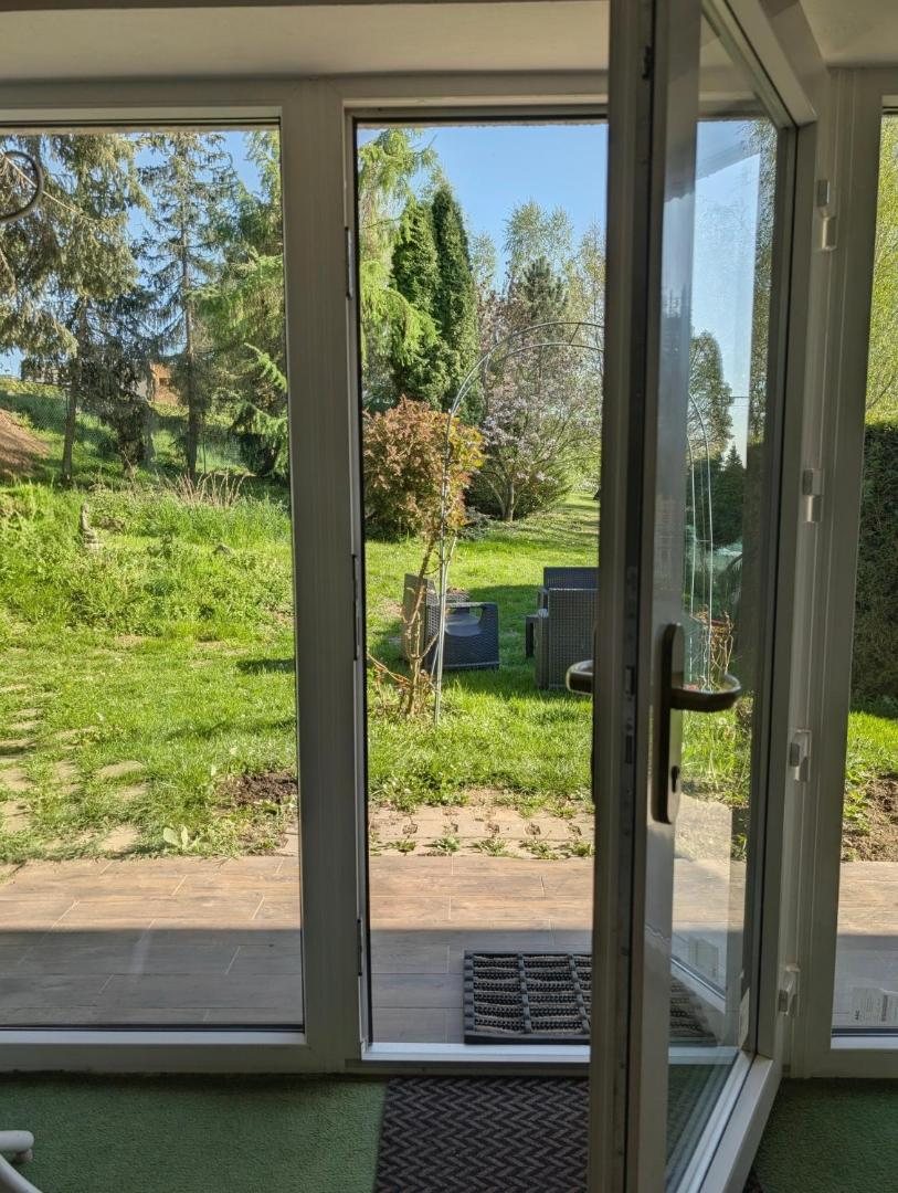 Pohled otevřenými dveřmi na trávník a stromy
